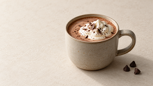 Hojicha hot chocolate topped with whipped cream and chocolate shavings in a ceramic mug.